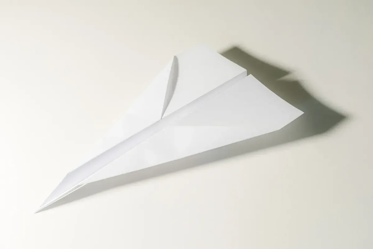 A paper plane made of white paper on a light background