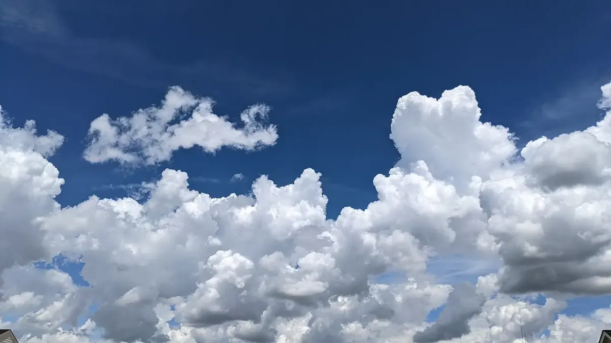 Towering white heap clouds against a deep blue sky