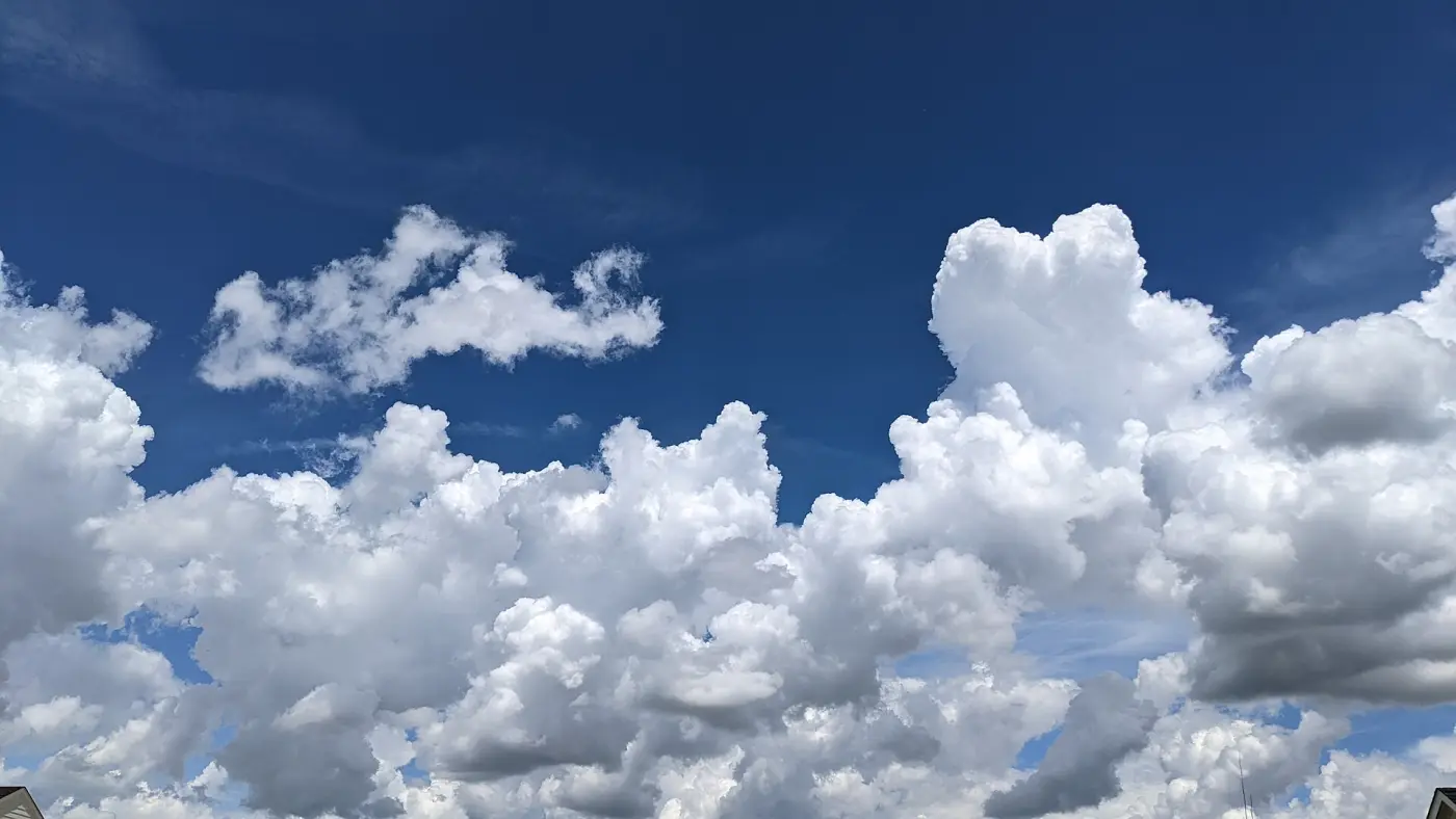 Towering white heap clouds against a deep blue sky