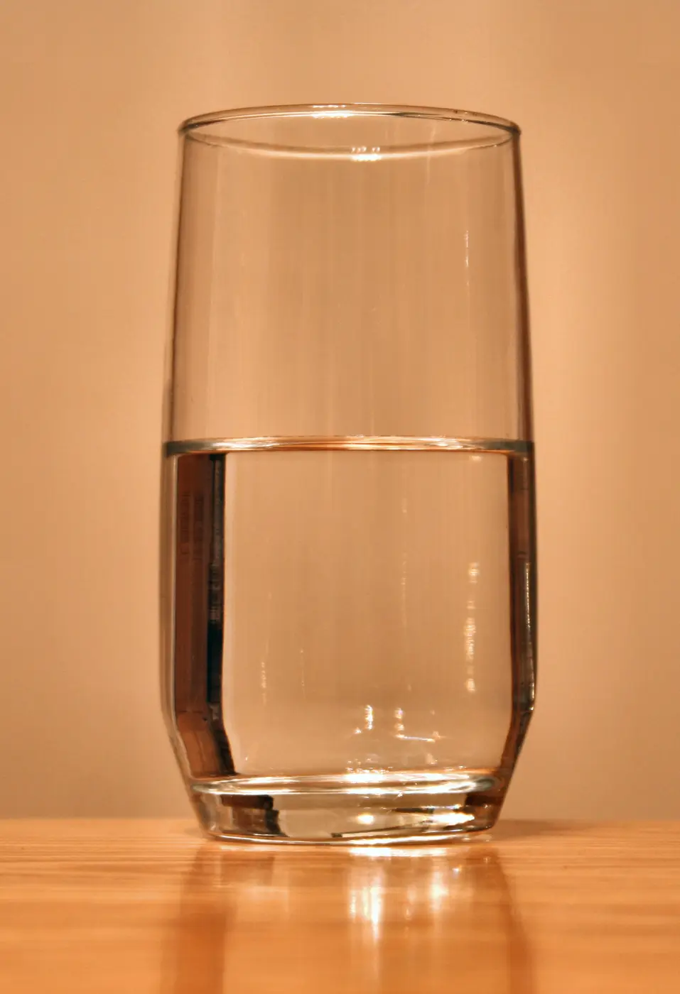 A half-full glass of water on a wooden table