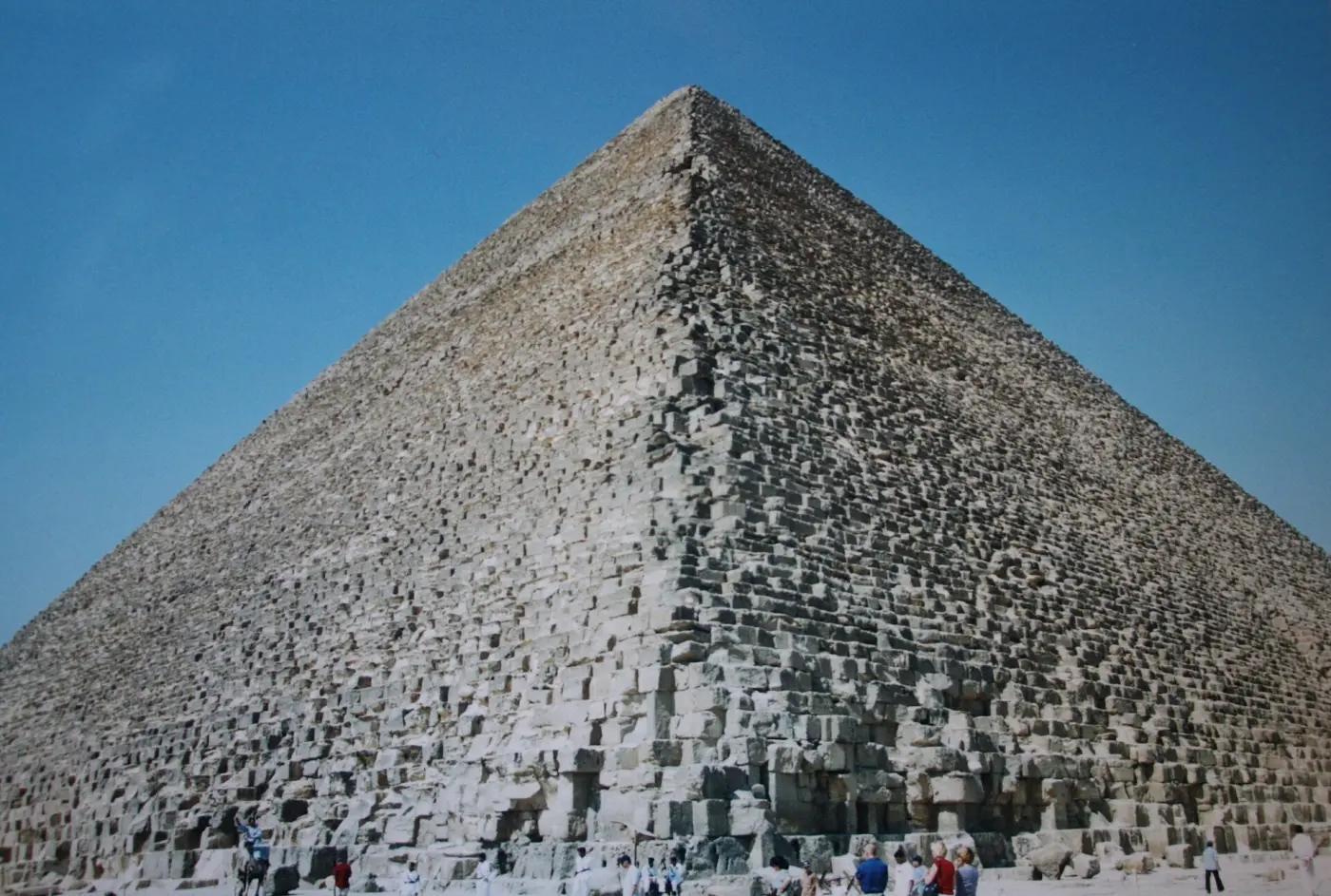 An edge of the Great Pyramid made of huge stone blocks against a deep blue sky
