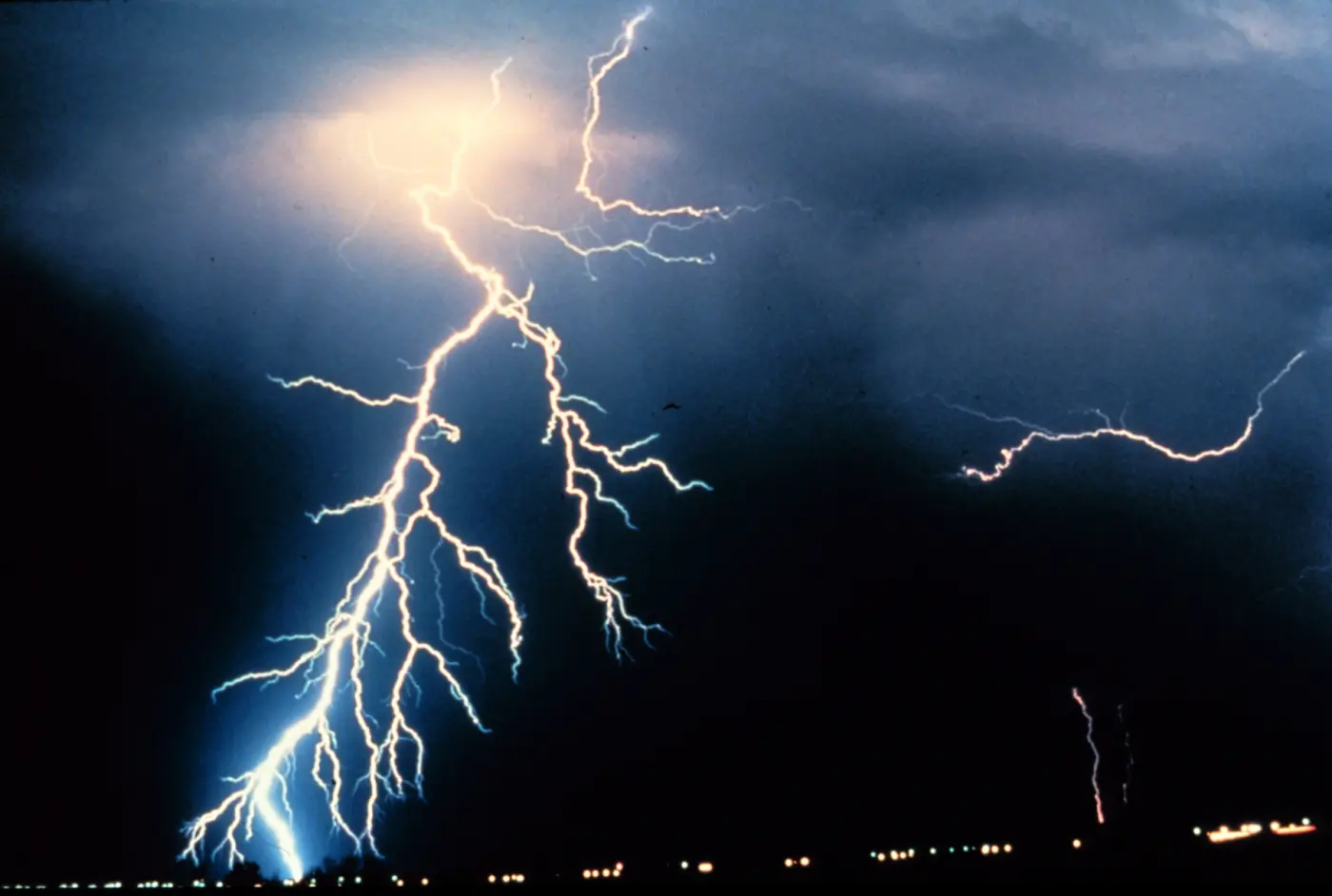 Several branching lightning bolts over a plain at night
