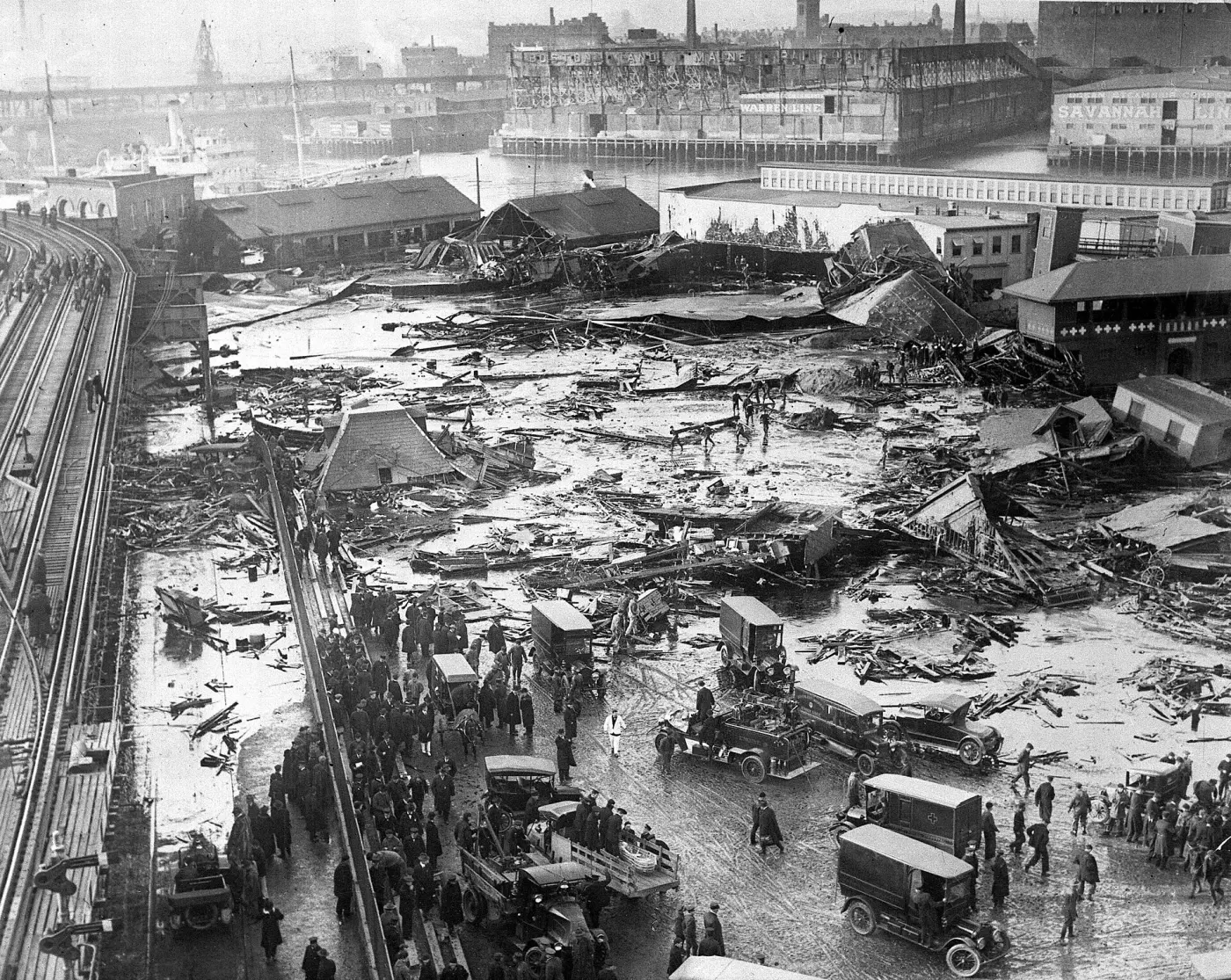 Wreckage in Boston's North End after the molasses flood, the elevated railway on the left, rescuers and vehicles in the foreground