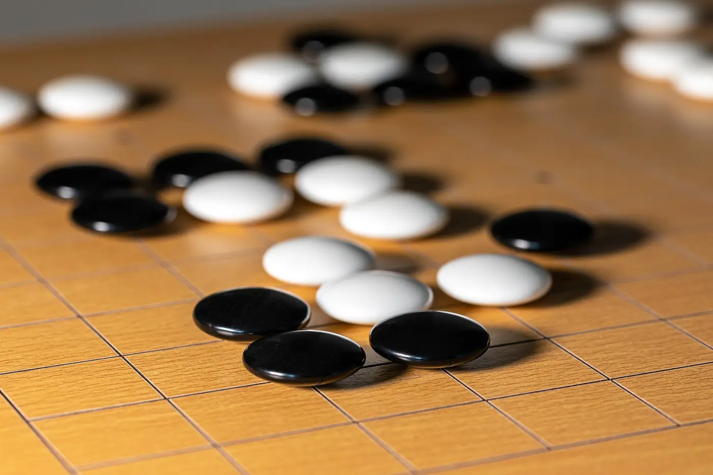 Black and white Go stones on a light wooden board with a grid of lines