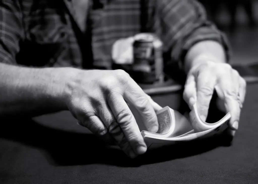 Black-and-white photo: two hands let the halves of a deck of cards fall into each other