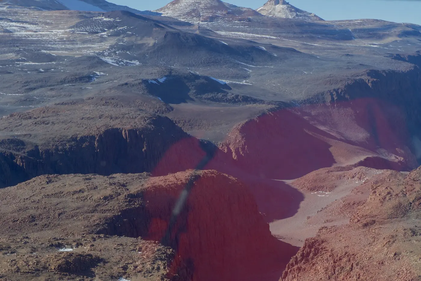 Bare, reddish-brown rocky valleys without snow, mountains behind: Antarctica's Dry Valleys