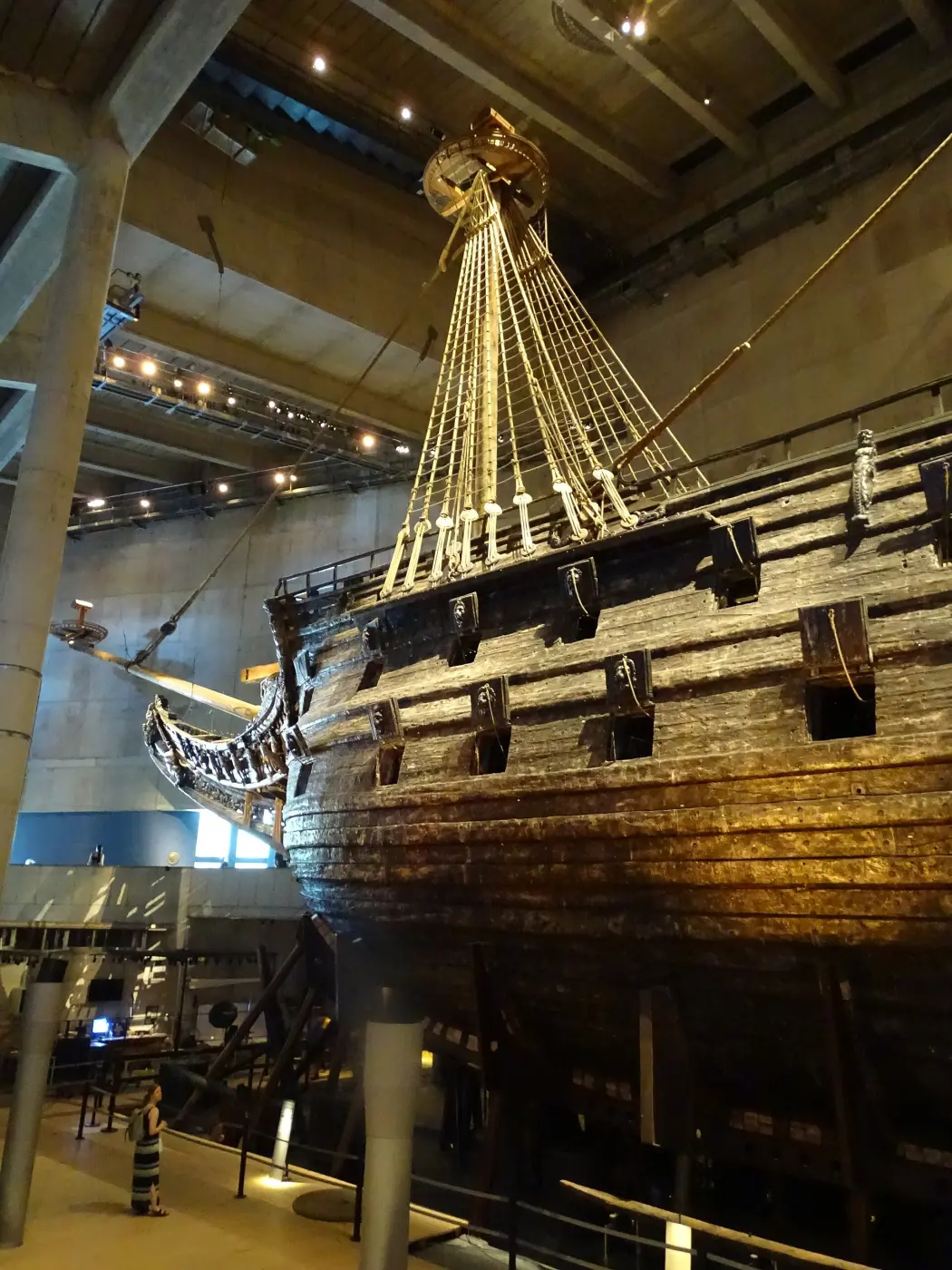 Das dunkle, reich verzierte Holzschiff Vasa mit Masten und Takelage in einer Museumshalle